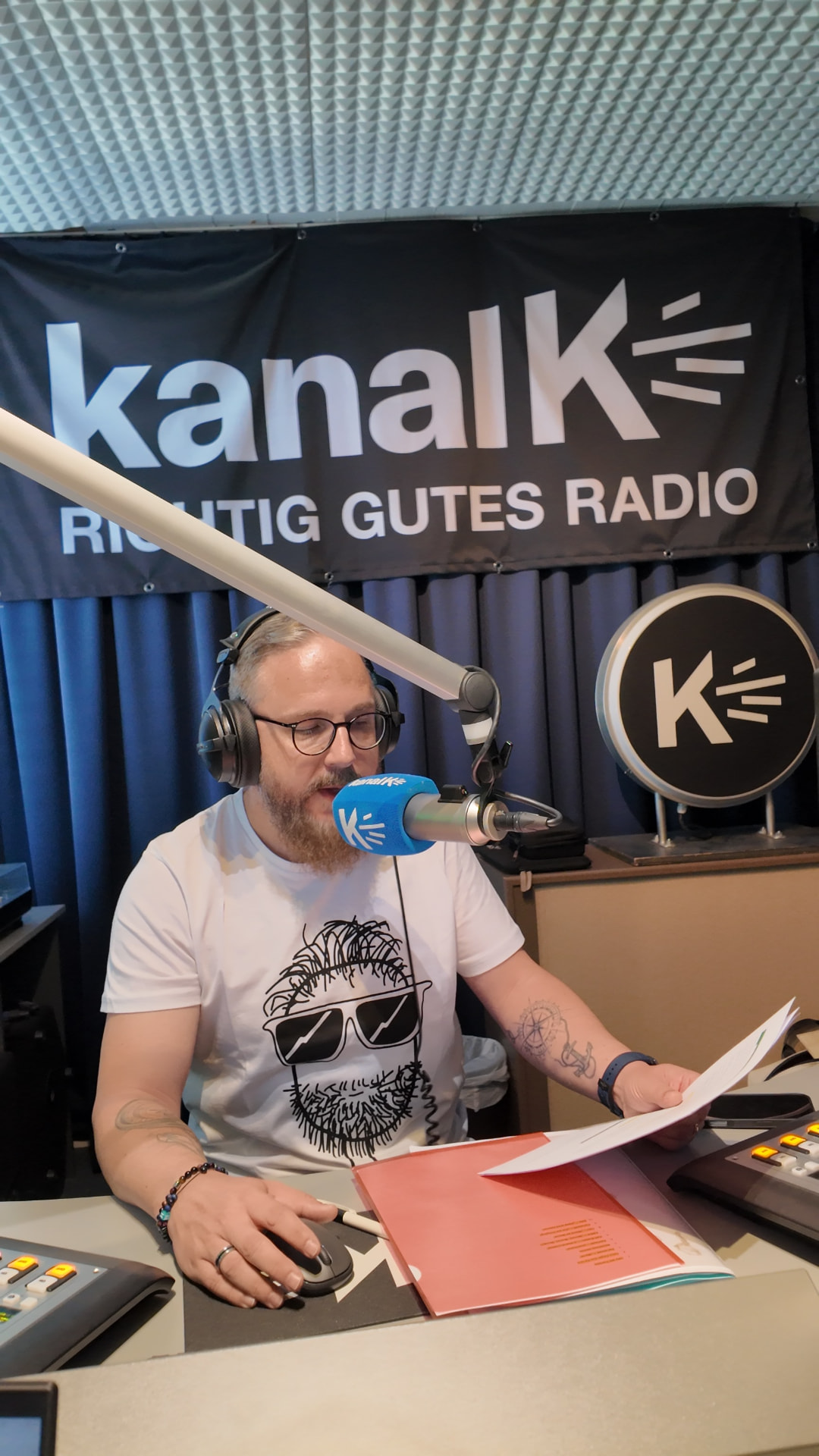 Nico Albert im Studio von Kanal K mit Skript und Moderationsunterlagen