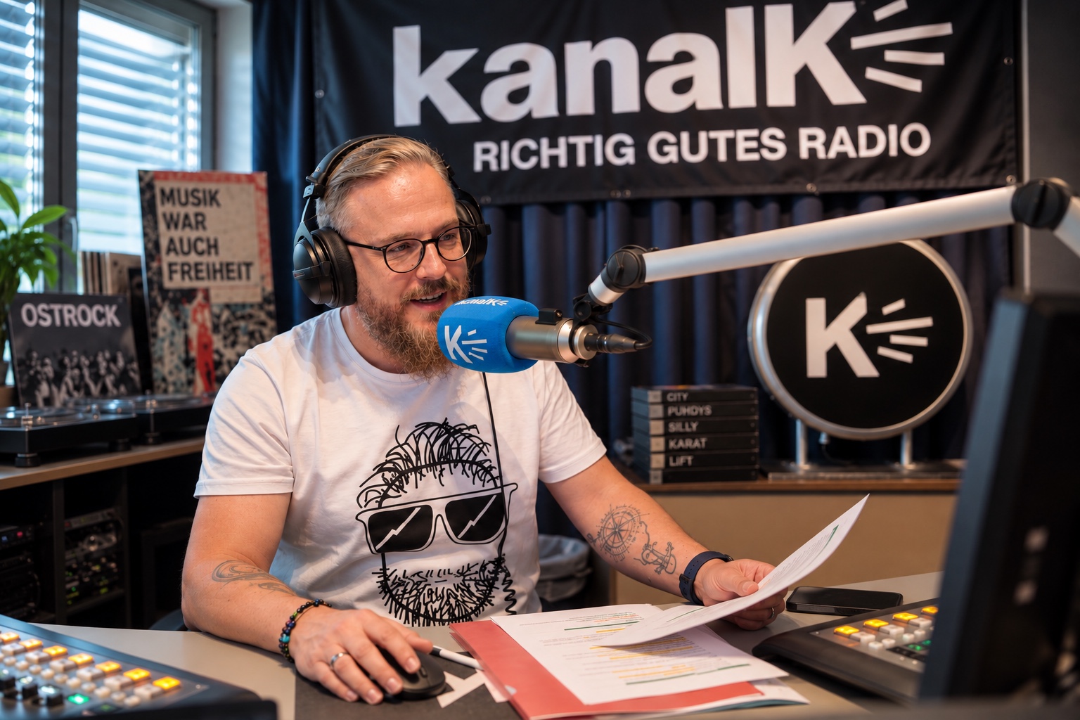 Nico Albert am Pult im Studio von Kanal K, im Hintergrund das Studiobanner